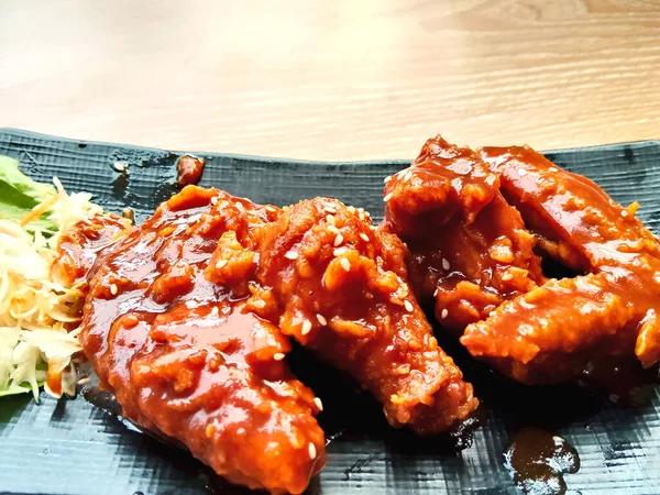 Yakın plan kızarmış tavuk kanadı kalın, baharatlı kırmızı sosla kaplanmış ve susam tohumlarıyla kaplanmış..