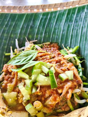 Muz yaprağında servis edilen ve üzerinde baharatlı fıstık sosu bulunan buharda pişirilmiş sebze karışımının yer aldığı geleneksel bir Endonezya Sundan yemeği..