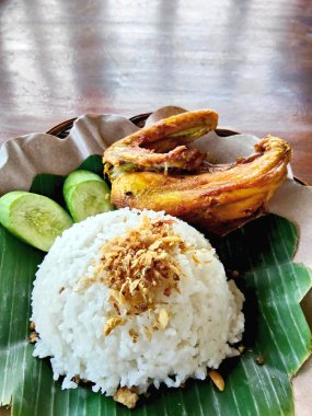 Bir tabak kızarmış tavuk kanadı yanında bir kepçe beyaz pirinç ve taze Endonezya Sundan salatası, ya da muz yaprağı üzerinde Lalapan..