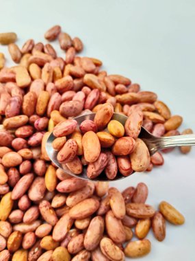 Kurumuş kırmızı fasulye yığını temiz beyaz bir arkaplan üzerine dağılmış ve izole edilmiş doğal dokularını sergiliyor..