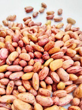 Kurumuş kırmızı fasulye yığını temiz beyaz bir arkaplan üzerine dağılmış ve izole edilmiş doğal dokularını sergiliyor..