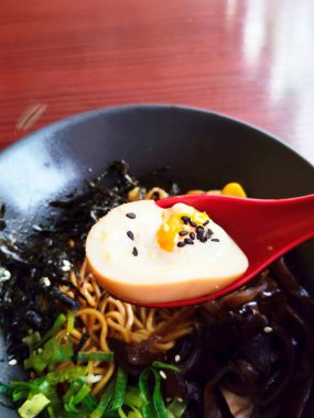 Bir el, lezzetli bir Japon kuru rameninden bir yığın erişte kaldırmak için çubuk kullanıyor.).