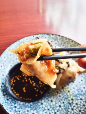 Nori ve susam tohumlarıyla süslenmiş altın, çıtır gyoza hamur tatlısı, güzel mavi ve beyaz bir tabakta servis edilir..