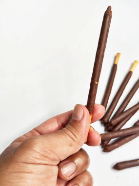 Çikolatayla kaplı tek bir çıtır bisküvi çubuğu tutan bir elin yakın plan çekimi..