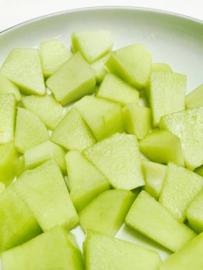 Beyaz bir kâseye istiflenmiş taze doğranmış kavun parçacıkları. Bu canlı yeşil görüntü sağlıklı atıştırmalıklar ve meyve salatası kavramları için mükemmeldir..