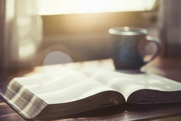 Zbliżenie Otwartej Biblii Filiżanką Kawy Poranne Nabożeństwo Drewnianym Stole Światłem — Zdjęcie stockowe