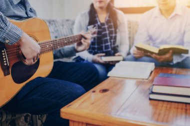 Genç bir adam gitar çalıyor ve Hıristiyan aile kavramı olan evde arkadaşlarıyla birlikte Hıristiyan ilahi kitabından bir şarkı söylüyor.
