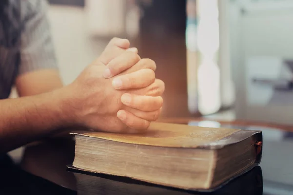 在家里坐在沙发上的时候 把一个人的手放在圣经上祈祷 — 图库照片