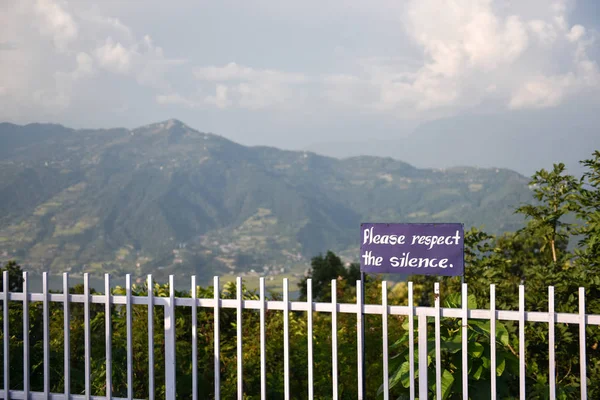 fence with please respect silence sign and mountainous landscape