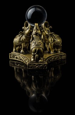 Cam bir top tutan ağaç filleri şeklinde bir figür.