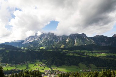 Schladming kasaba Dachstein Dağları arka plan, Kuzey kireçtaşı Alpler, Avusturya, dramatik bulutlu gökyüzü ile üzerinde uçan yamaçparaşütü