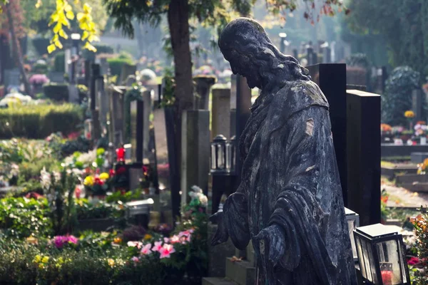 Jesus Christ statue among graves, autumn on cemetery, Prague, Czech Republic, sunny day, All souls day concept