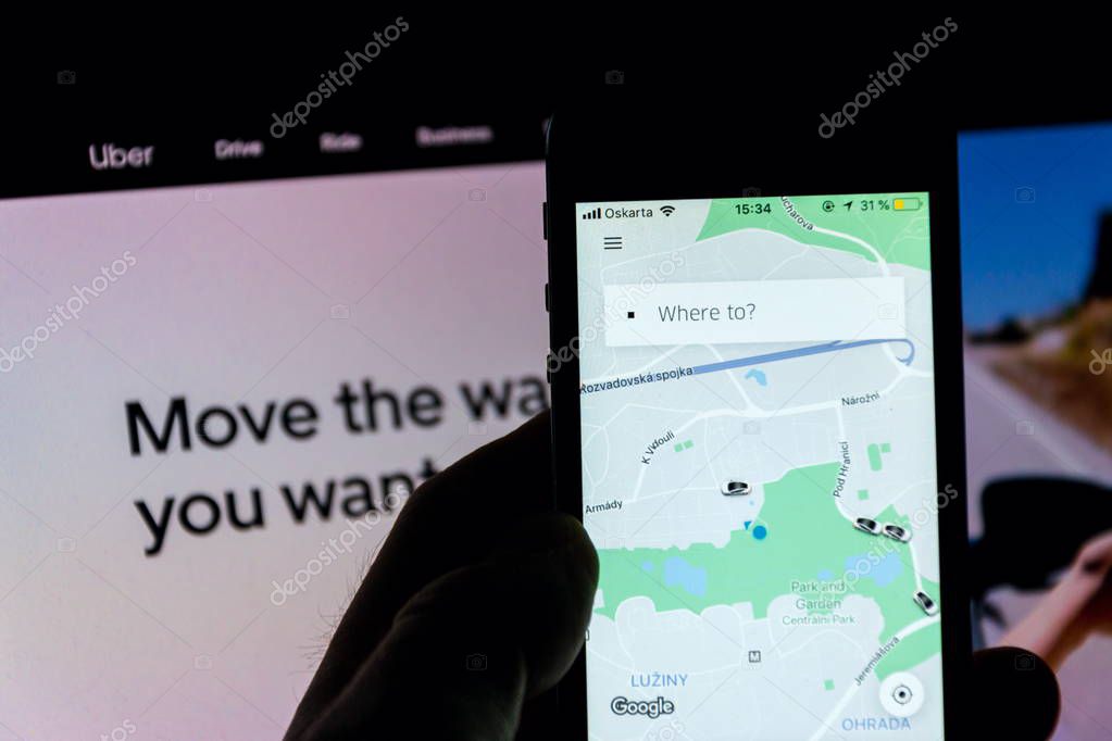 PRAGUE, CZECH REPUBLIC - NOVEMBER 21 2018: Uber company mobile app on phone screen with internet homepage in background on November 21, 2018 in Prague, Czech republic.