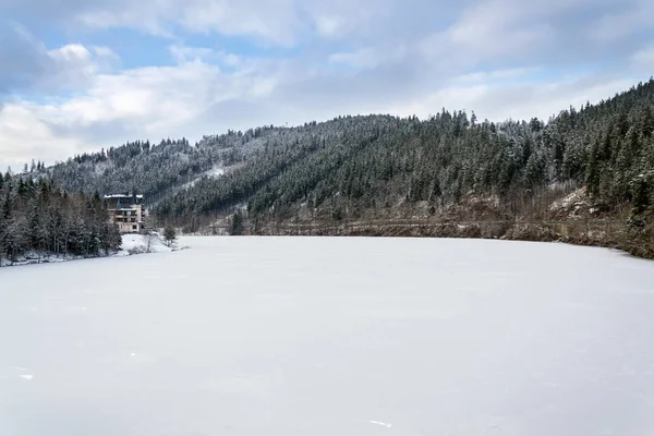 孤独的酒店建筑在一个美丽的雪天景观与森林和冻结的布雷佐娃大坝 — 图库照片