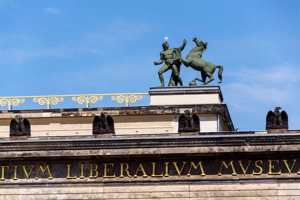 Horse with man bronze sculpture on the roof of Old Museum - Altes Museum in Berlin, Germany, inscription on portico reads Friedrich Wilhelm III has dedicated this museum to the study of all antiquities and the liberal arts, 1828