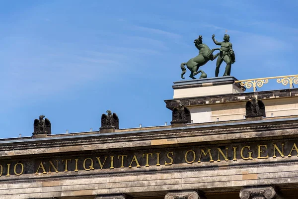 Horse with man bronze sculpture on the roof of Old Museum - Altes Museum in Berlin, Germany, inscription on portico reads Friedrich Wilhelm III has dedicated this museum to the study of all antiquities and the liberal arts, 1828