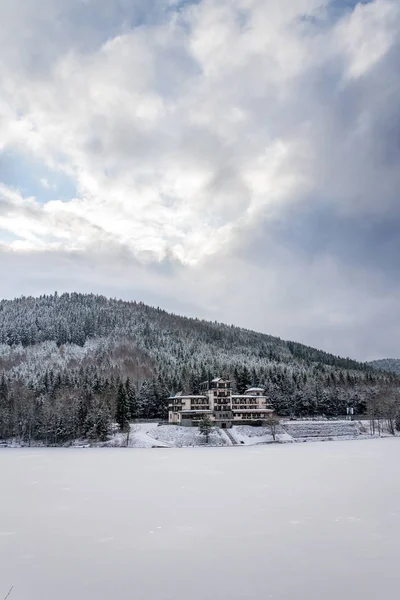 Solitary building in beautiful snowy winter forest landscape, frozen Brezova dam, Shining movie style