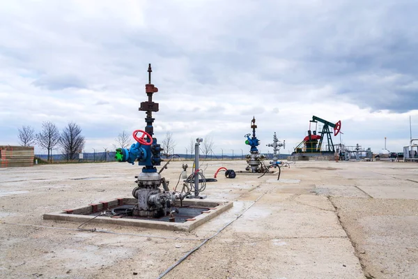 Green and red pumpjack, oil horse, oil derrick pumping oil well with dramatic cloudy sky background