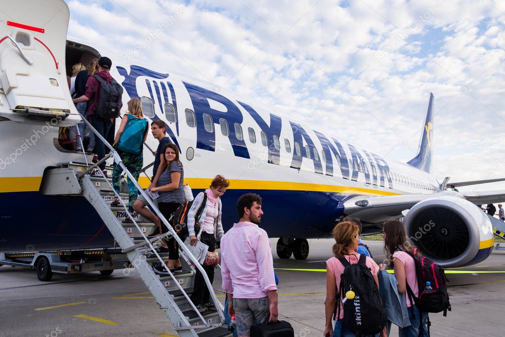 MEMMINGEN, GERMANY - JULY 6 2019: People boarding Ryanair Irish low-cost airline plane Boeing 737 with cloudy sky background on July 6, 2019 in Memmingen, Germany.