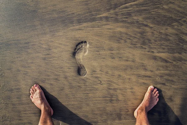 Human footprint with barefoot feet in brown yellow sand beach background, active healthy living and personal growth concept, copy space