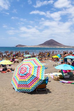 El Medano, İspanya - 7 Temmuz 2019: 7 Temmuz 2019'da İspanya'nın El Medano kentinde playa El Medano plajında yüzen ve güneşlenen insanlar.