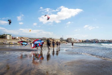 El Medano, İspanya - 7 Temmuz 2019: İnsanlar 7 Temmuz 2019 tarihinde İspanya 'nın El Medano kentinde Granadilla de Abona belediyesinde Playa de Leocadio Machado plajında sörf, uçurtma ve rüzgar sörfü yapıyorlar..