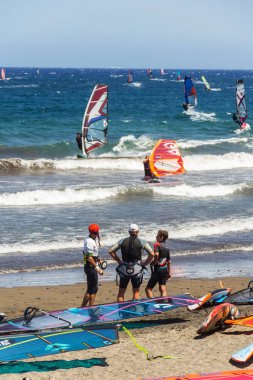 El Medano, İspanya - 7 Temmuz 2019: İnsanlar 7 Temmuz 2019 tarihinde İspanya 'nın El Medano kentinde Granadilla de Abona belediyesinde Playa de Leocadio Machado plajında sörf, uçurtma ve rüzgar sörfü yapıyorlar..
