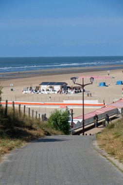 Kum tepelerinin yakınındaki güzel kumsaldaki insanlar Batı Flanders, güneşli yaz günü 23 Mayıs 2025, De Haan, Belçika.