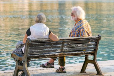 Cefalu, İtalya, 2 Kasım 2017: su kenarındaki parkta bankta oturan yaşlı çift