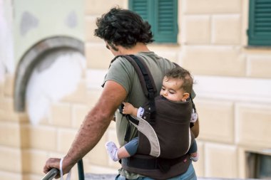 Bogliasco, İtalya, 6 Ekim 2017: Kentin arkasından bir askı içinde Bebekli adam