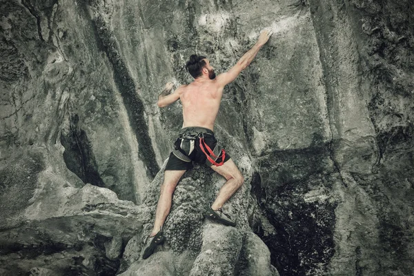 若いあごひげの男が保険なしで岩を登っている トーン — ストック写真