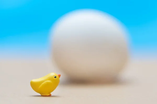 小玩具黄色小鸡附近的大白鸡蛋在蓝色背景 — 图库照片