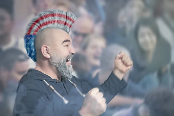 Sport supporter with Iroquois haircut in colors of America flag during a soccer or football match at the stadium