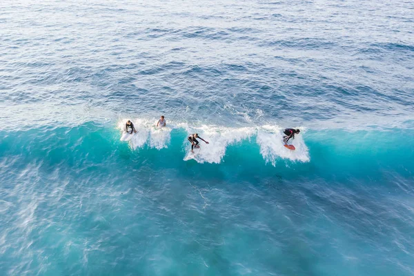 Four Surfers at the top of the wave, top view