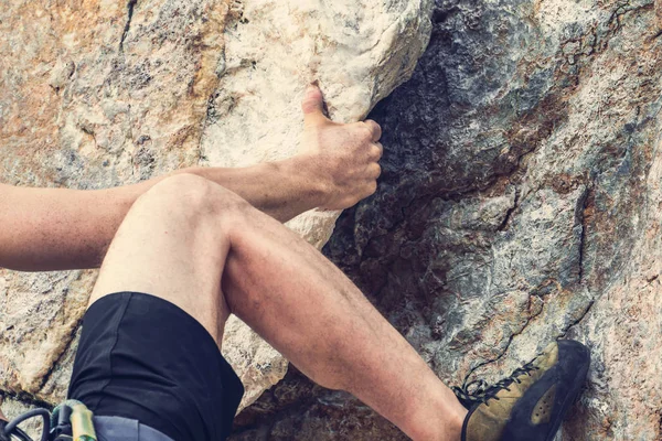 Rock climber holding his hand over a ledge of a cliff, close-up