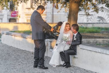 Roma, İtalya, 21 Ekim 2017: Profesyonel kameramanların parkta bir bankta oturmuş yeni evlilere vuruyor