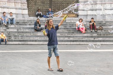 Genoa, İtalya, 6 Ekim 2017: Genç bir adam sokakta büyük sabun köpüğü yapar