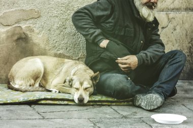Sokakta dilenci yaşlı adam bir köpek ile sokakta yalvarıyor
