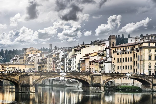 People on the bridge over the Arno River on a cloudy day, Florence, Italy