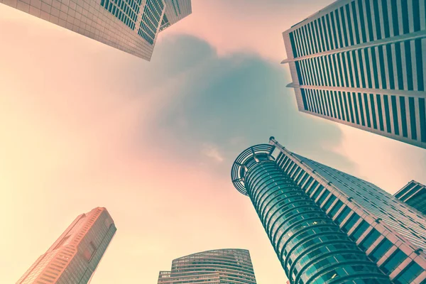 Business concept for real estate and corporate construction - looking up view in financial district. Skyscrapers at sunset