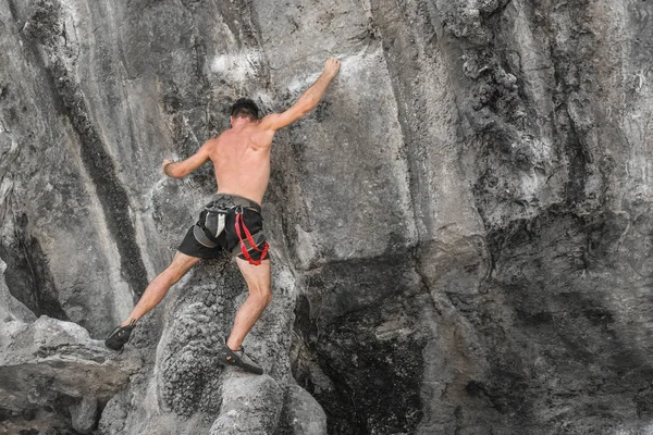 若い男性登山保険機器なしで岩壁を登る — ストック写真