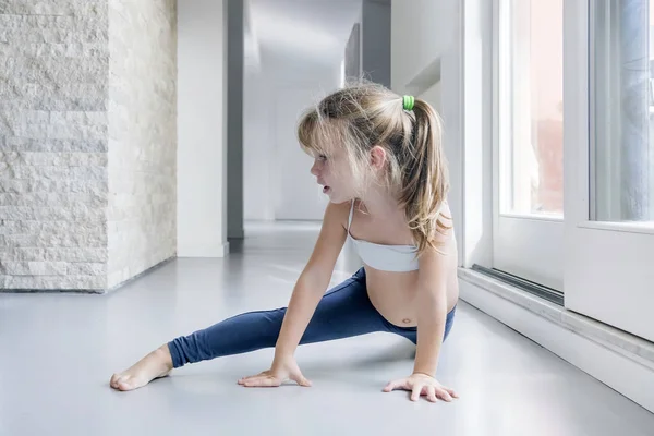 窓の近くの部屋で体操をしている金髪少女 — ストック写真