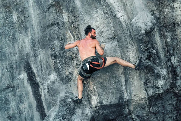 若いひげを生やした男性クライマーは保険なしで崖を登る — ストック写真