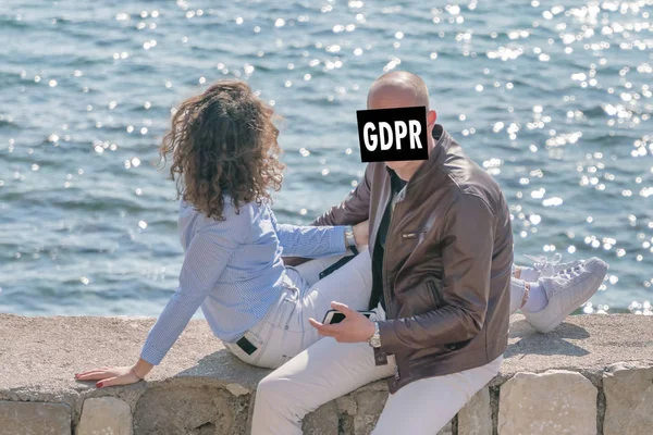 Couple resting by the sea. The man\'s face is hidden behind the inscription GDPR. Data Protection Regulation. Cyber security and privacy.