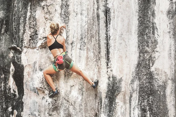 若い女性のロッククライミング安全装置なしで崖を登ると スペースをコピーします トーン — ストック写真