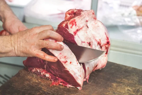 Butcher cuts a piece of meat with a knife