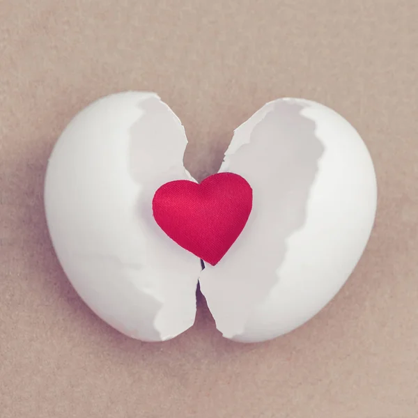 小红色的心脏孵化从一个白色的鸡蛋在褐色背景 — 图库照片
