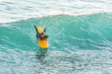 Bogliasco, İtalya, 6 Ekim 2017: Sörfçü yalan bir sarı sörf tahtası ve bir dalga binmek