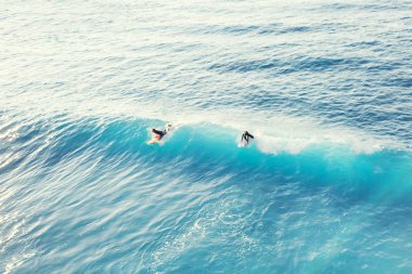 Dalga okyanusun üstten görünüm üstündeki iki sörfçü