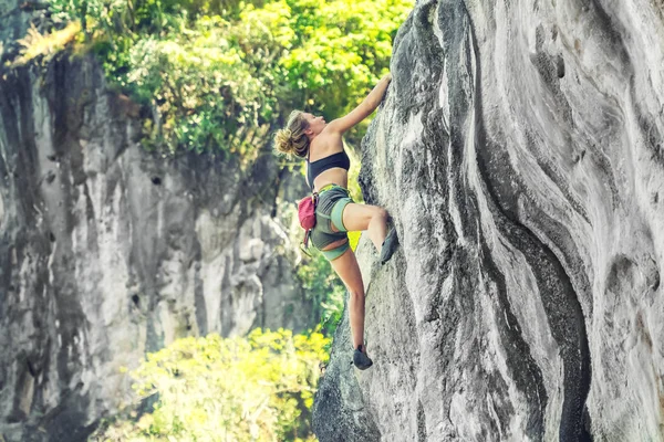 A woman climber climbs the cliff